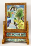 A LARGE HEAVY CHINESE CLOISONNE ENAMEL TABLE SCREEN in a brass frame, depicting trees and a river,