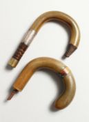 TWO RHINO HORN WALKING STICK HANDLES, one with silver collar.