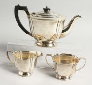 A THREE PIECE SILVER TEA SET comprising tea pot with ebony handle, sugar basin and milk jug.