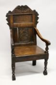 AN 18TH CENTURY OAK ARMCHAIR, with carved cresting rail and panelled back, solid seat and curving