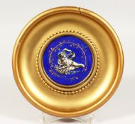 A GILT FRAMED CIRCULAR PORCELAIN PLAQUE, decorated with a cherub holding a basket of fruit 8ins