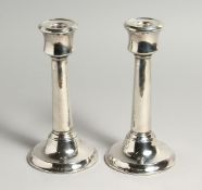 A PAIR OF PLAIN CIRCULAR SILVER CANDLESTICKS with leaded bases. 8ins high, London, 1901