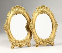 A PAIR OF GILT BRONZE OVAL EASEL MIRRORS 9ins x 6.5ins
