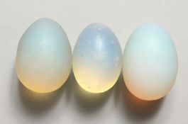 THREE BLUE OPALITE STONES of ovoid form, refracting orange light. Each 2ins long
