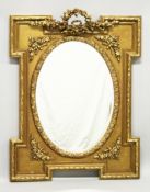 A DECORATIVE GILT FRAMED WALL MIRROR with a shaped rectangular frame and an oval mirror plate. 3ft