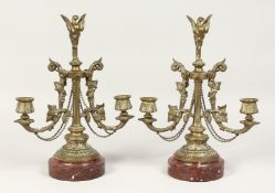 A PAIR OF 19TH CENTURY BRONZE TWO BRANCH LIGHTS on a circular marble base. 12ins high.