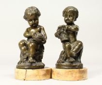 A GOOD PAIR OF EARLY 19TH CENTURY BRONZES OF SEATED PUTTI on circular marble bases. 4ins high