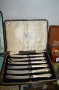 A cased set of six silver handled butter knives.