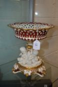 A good porcelain centrepiece, the base modelled with three cherubs.