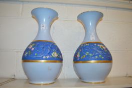 A pair of blue porcelain vases with a band of floral decoration.