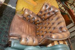 A Georgian style leather button upholstered and brass studded wing armchair.