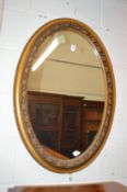 A gilt framed oval wall mirror.
