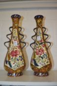 A pair of Hungarian pottery vases with moulded handles and floral decoration (one restored).