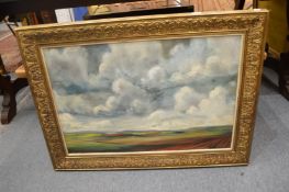 A barren landscape with stormy clouds, oil on board, in a decorative gilt frame.