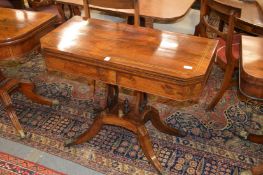 A Regency rosewood and brass inlaid foldover card table, the rectangular top with clipped corners on