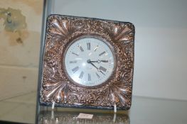 A desk clock with embossed silver frame.