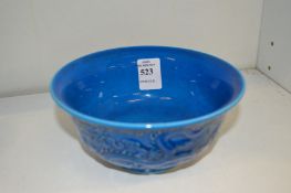 A Chinese blue glazed bowl with moulded dragon decoration.