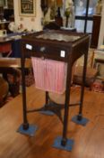 A mahogany sewing table with gallery top, a small drawer and a cloth bag below on square supports.