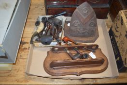 A collection of pipes, a pipe rack and a carved shield.