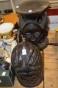 A large carved wood helmet mask and an African stool carved with masks.