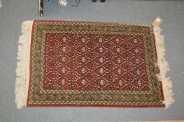 A small Persian rug, red ground with geometric decoration.