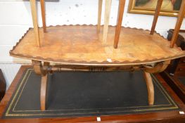 A burrwood oval shaped coffee table with galleried top on X-shaped supports.