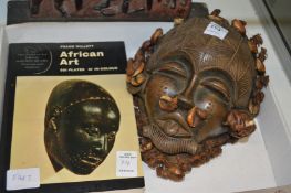 An African pottery mask together with a book on African art.