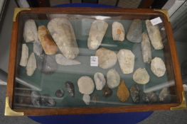 A mahogany display case containing a good collection of stone axes, flint spear and arrow heads