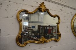 A decorative gilt framed mirror with scrolling frame.