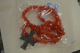 A red bead necklace mounted with a small bronze cross.