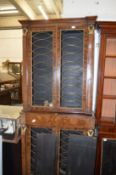 A Regency design rosewood floor standing, two part, four door bookcase, the brass grilled doors