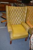 A Georgian style leather button upholstered and brass studded wing armchair.