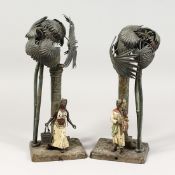 A VERY GOOD PAIR OF VIENNA PAINTED COLD CAST LAMPS, figures standing beside a column and palm trees.
