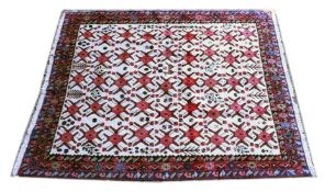 A PERSIAN CARPET, cream ground with stylised red ground medallions. 8ft 2ins x 6ft 6ins.