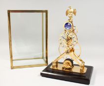 A BRASS SKELETON MOONPHASE CLOCK in a glass case. 17ins high.