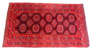 A PERSIAN TEKKE BOKHARA DESIGN RUG, red ground with lozenge shaped medallions. 6ft 6ins x 3ft