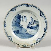 A DELFT TIN GLAZED BLUE AND WHITE PLATE painted with a house on a river 9ins diameter.