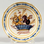 A SMALL DELFT TIN GLAZE CIRCULAR PLATE painted with flowers 6.25ins diameter.