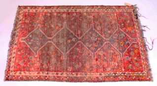A PESIAN TEKKE DESIGN RUG, red ground with four large central diamond shaped medallions. 5ft 10ins x