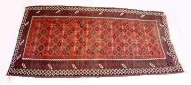 A PERSIAN TEKKE DESIGN RUG, red ground with geometric stylised design. 7ft 10ins x 4ft 2ins.