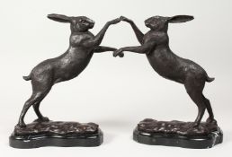 A PAIR OF BRONZE BOXING HARES on shaped marble bases. 11.5ins high.