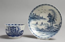 AN 18TH CENTURY WORCESTER TEA BOWL AND SAUCER painted with a tree on an island and two sailing boats