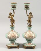 A PAIR OF PORCELAIN AND GILT METAL CHERUB CANDLESTICKS.