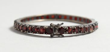 A SILVER GARNET SET BANGLE.