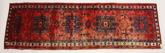 A PERSIAN HERIZ RUNNER, red ground with four large medallions (some wear). 10ft 4ins x 3ft 3ins.
