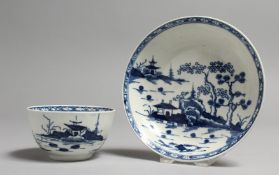 AN 18TH CENTURY WORCESTER TEA BOWL AND SAUCER painted with an island house, a rock and two trees