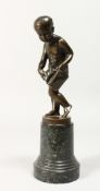 A GOOD BRONZE OF A NUDE YOUNG BOY holding a bag, on a circular marble base. 7.5ins high.