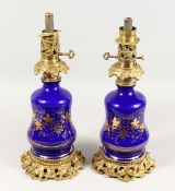 A GOOD PAIR OF 19TH CENTURY BLUE GLASS AND GILT METAL LAMPS decorated in gilt with fruiting vines.