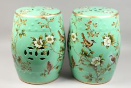 A PAIR OF GREEN CHINESE PORCELAIN BARREL SEATS with flowers and birds. 17.5ins high.