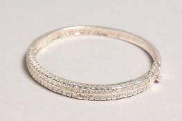 A SILVER CUBIC ZIRCONIA BANGLE.